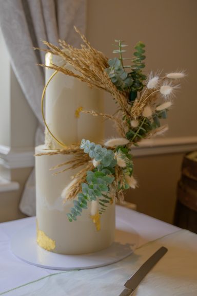A two-tiered cake adorned with dried flowers and greenery.